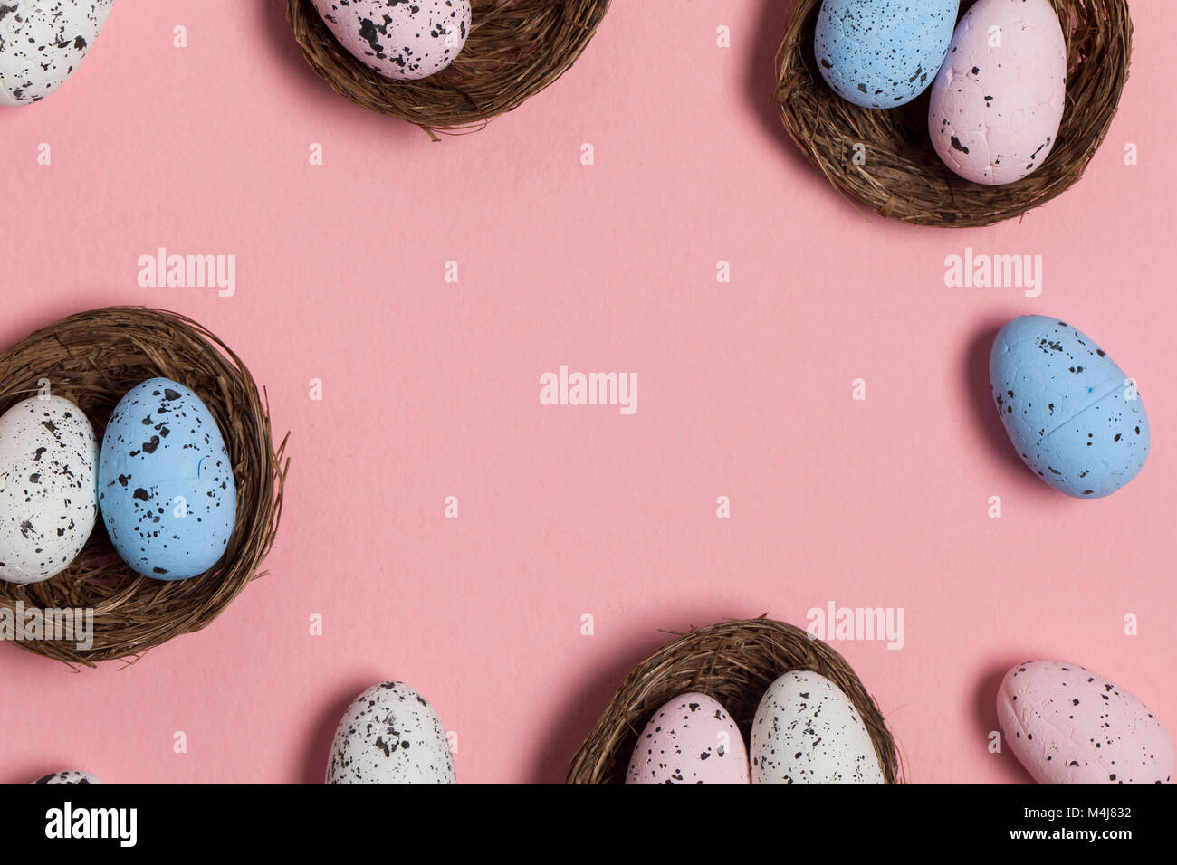 Uova di Pasqua in un nido su un pastello sfondo rosa Foto Stock