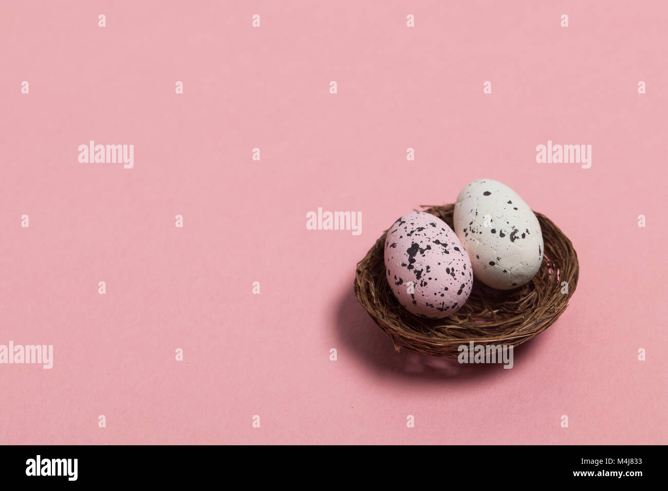 Uova di Pasqua in un nido su un pastello sfondo rosa Foto Stock
