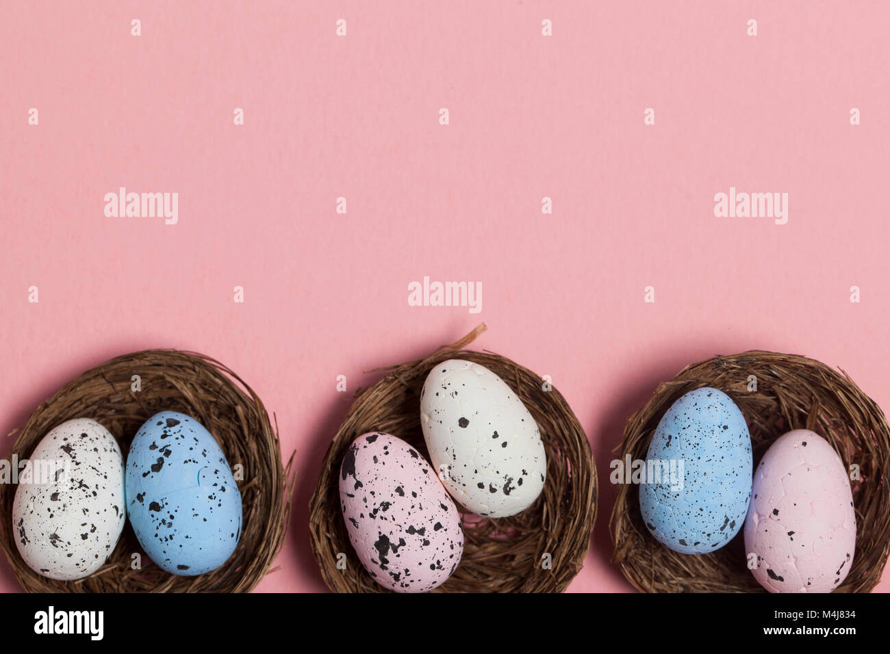 Uova di Pasqua in un nido su un pastello sfondo rosa Foto Stock