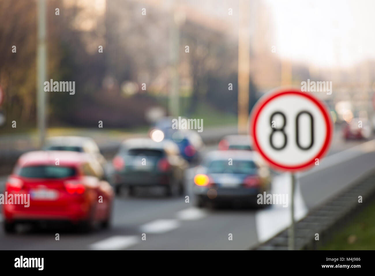 Immagine sfocati di segno di traffico che mostra 80 km/h il limite massimo di velocità su una strada piena di automobili Foto Stock