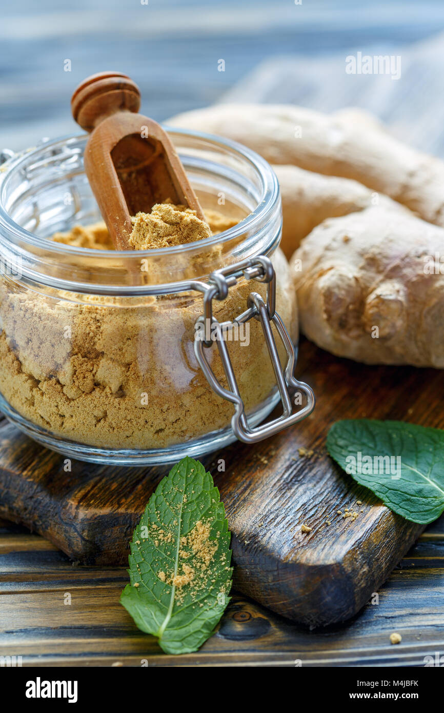 Lo zenzero in polvere in un recipiente di vetro e di zenzero fresco. Foto Stock