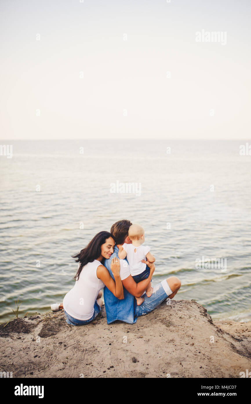 Tema Vacanza In Famiglia Con Bambino Piccolo Sulla Natura E Sul Mare Mamma Papa E La Figlia Di Un Anno Sono In Seduta Abbraccio Ragazze Nelle Mani Di Uomo Wit Foto Stock