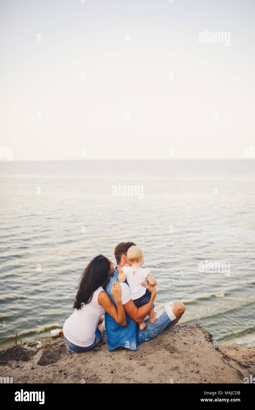 Tema Vacanza In Famiglia Con Bambino Piccolo Sulla Natura E Sul Mare Mamma Papa E La Figlia Di Un Anno Sono In Seduta Abbraccio Ragazze Nelle Mani Di Uomo Wit Foto Stock