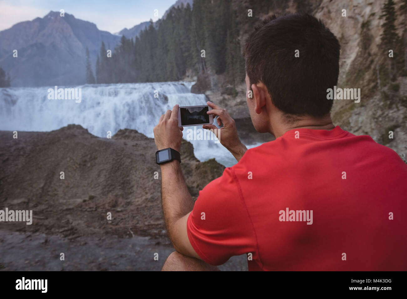 L'uomo prendendo foto di cascata con telefono mobile Foto Stock