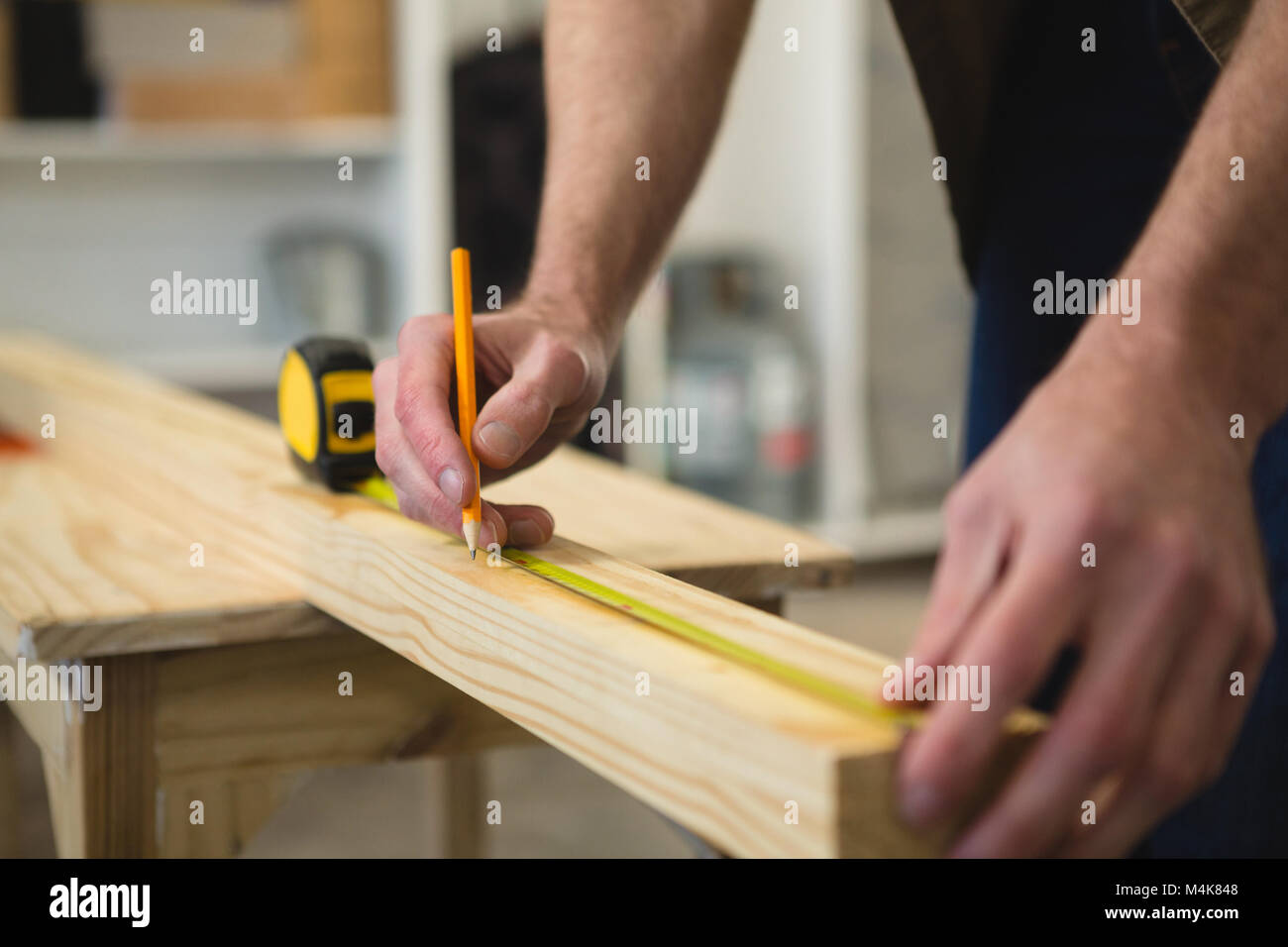 Maschio misura falegname e marcatura di legno in officina Foto Stock