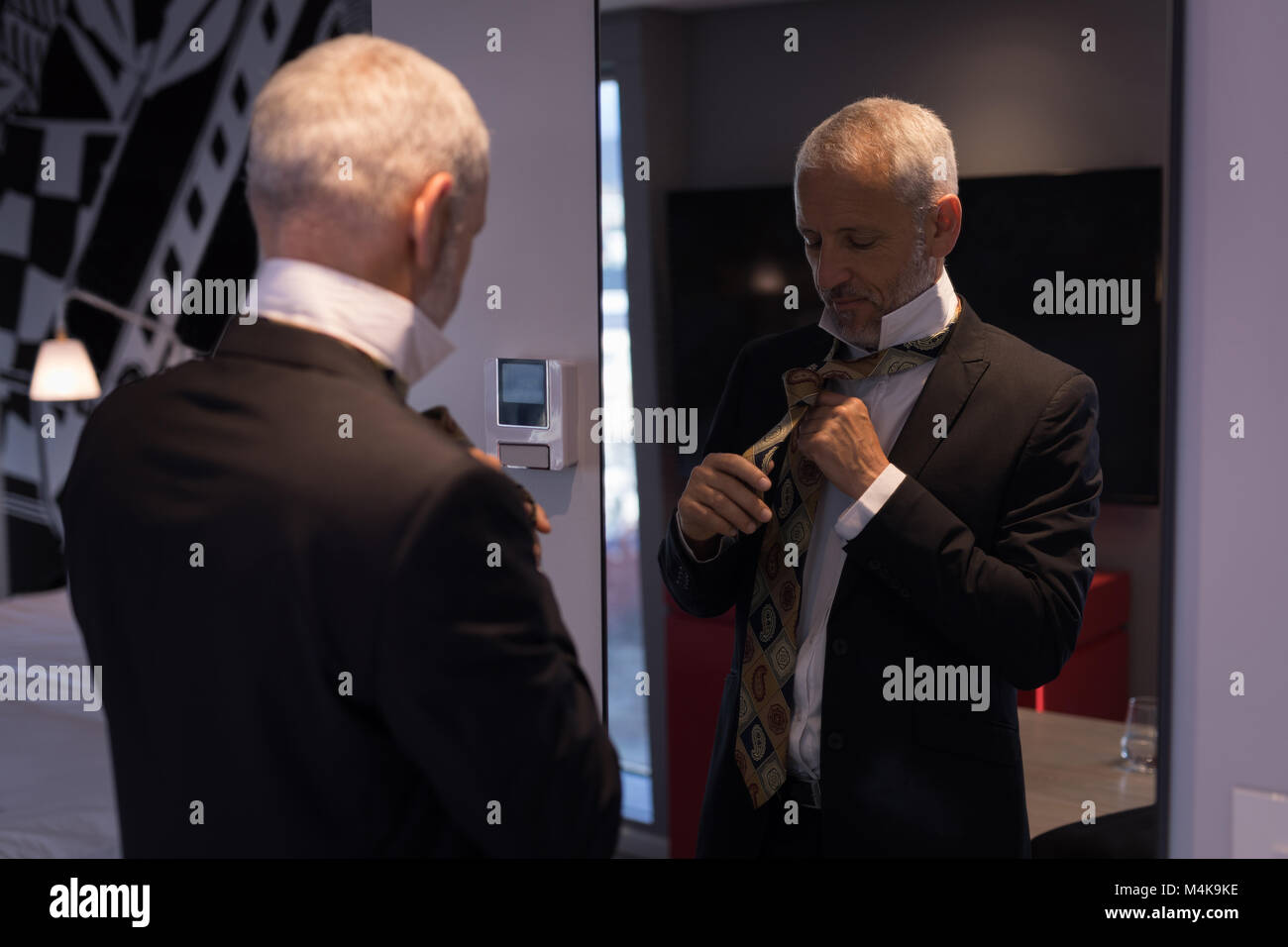 Imprenditore la legatura la cravatta di fronte a uno specchio Foto Stock