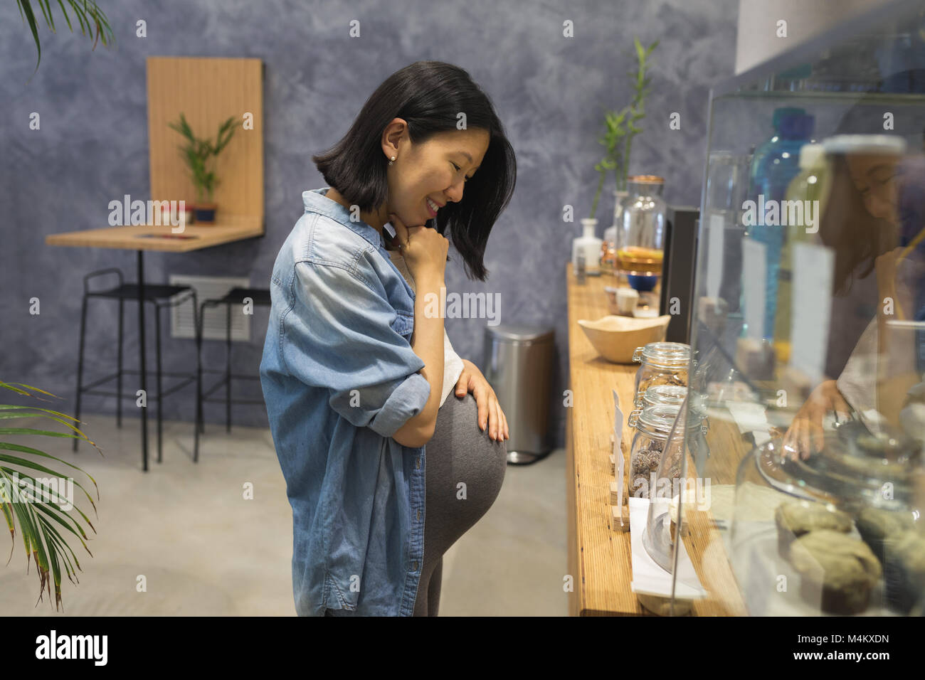 Incinta imprenditrice guardando sweet food nella caffetteria Foto Stock