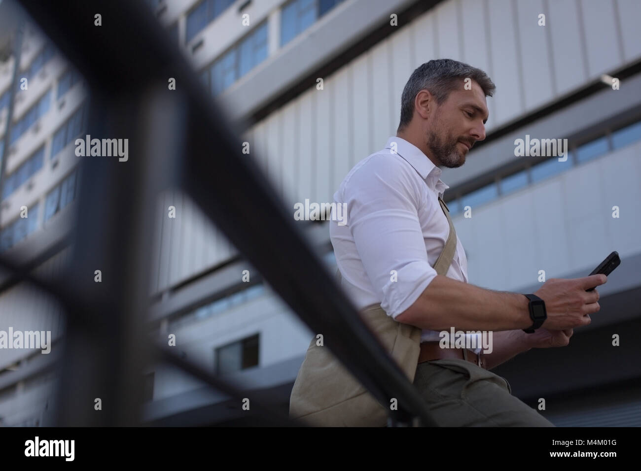 Uomo che utilizza il telefono cellulare vicino edificio per uffici Foto Stock