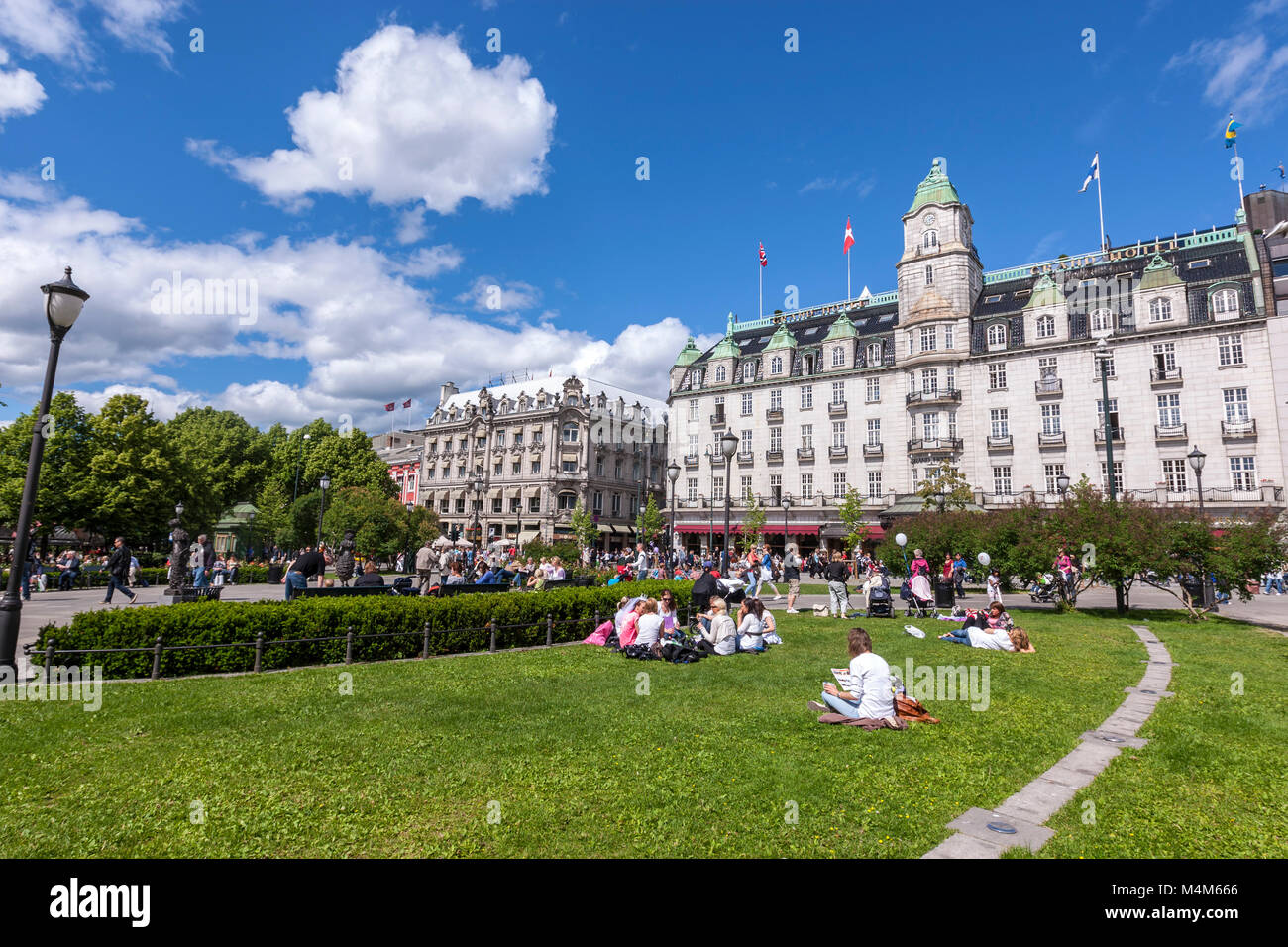 La gente seduta in erba in un parco al Grand Hotel di Oslo Karl Johans gate, Oslo, Norvegia Foto Stock