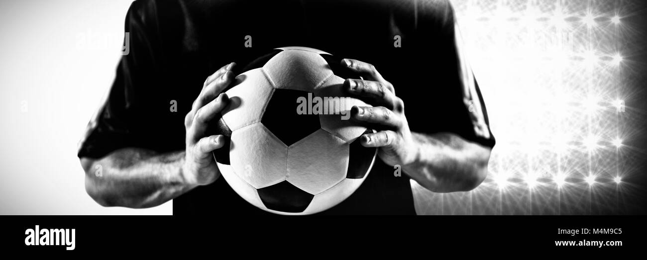 Immagine composita della sezione intermedia del giocatore di football in jersey nero sfera di trattenimento Foto Stock Immagine composita della sezione intermedia del giocatore di football in jersey nero sfera di trattenimento Foto Stock