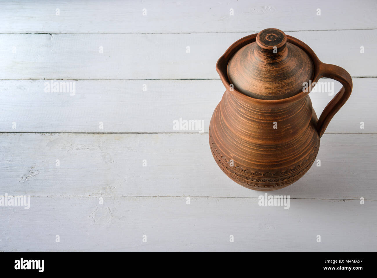 Brocca di argilla sul tavolo di legno dello sfondo. Vista dall'alto. Spazio di copia Foto Stock