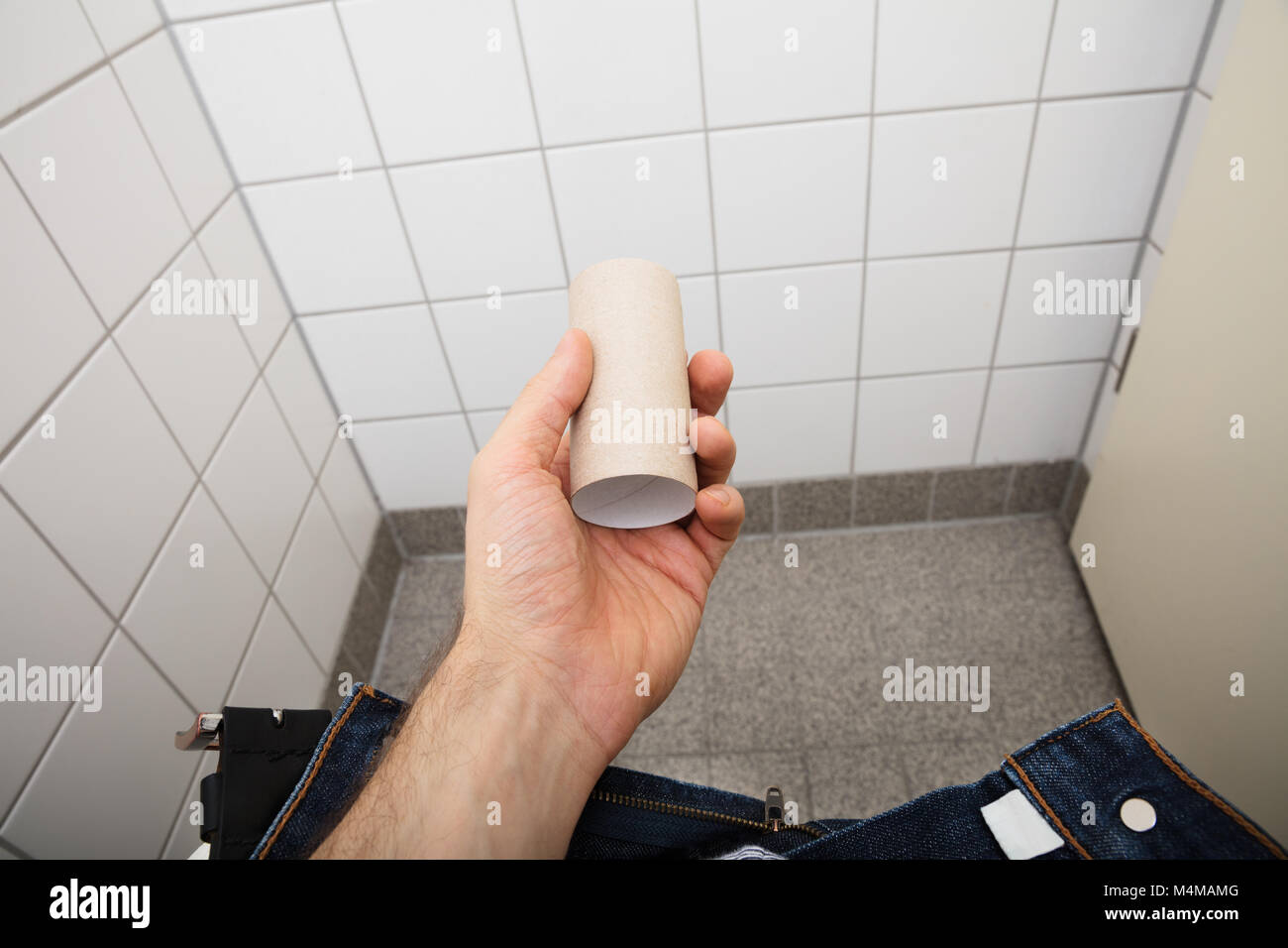 Close-up di una mano di un uomo azienda vuoto di carta igienica rotolo nel bagno Foto Stock