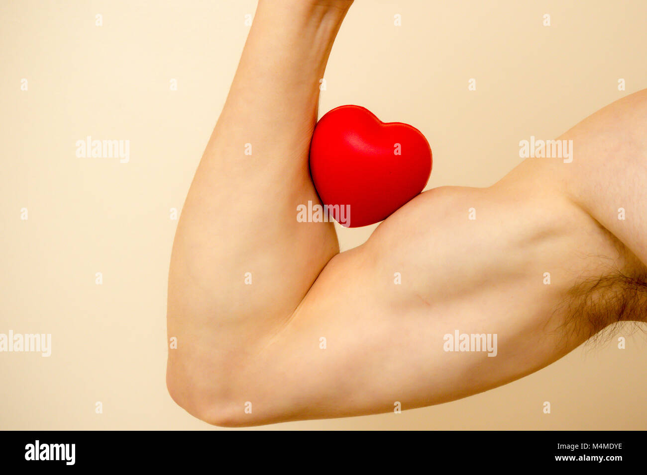 Tenendo un cuore rosso contro un muscolo bicipite per il giorno di san valentino Foto Stock