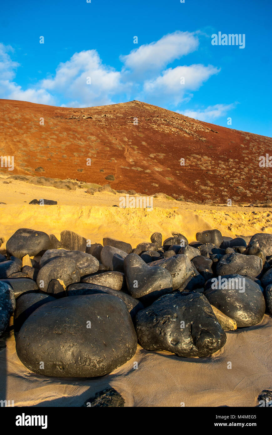 Pietre Nere sulla spiaggia con la montagna dietro, Graciosa Island, Isole Canarie, Spagna Foto Stock