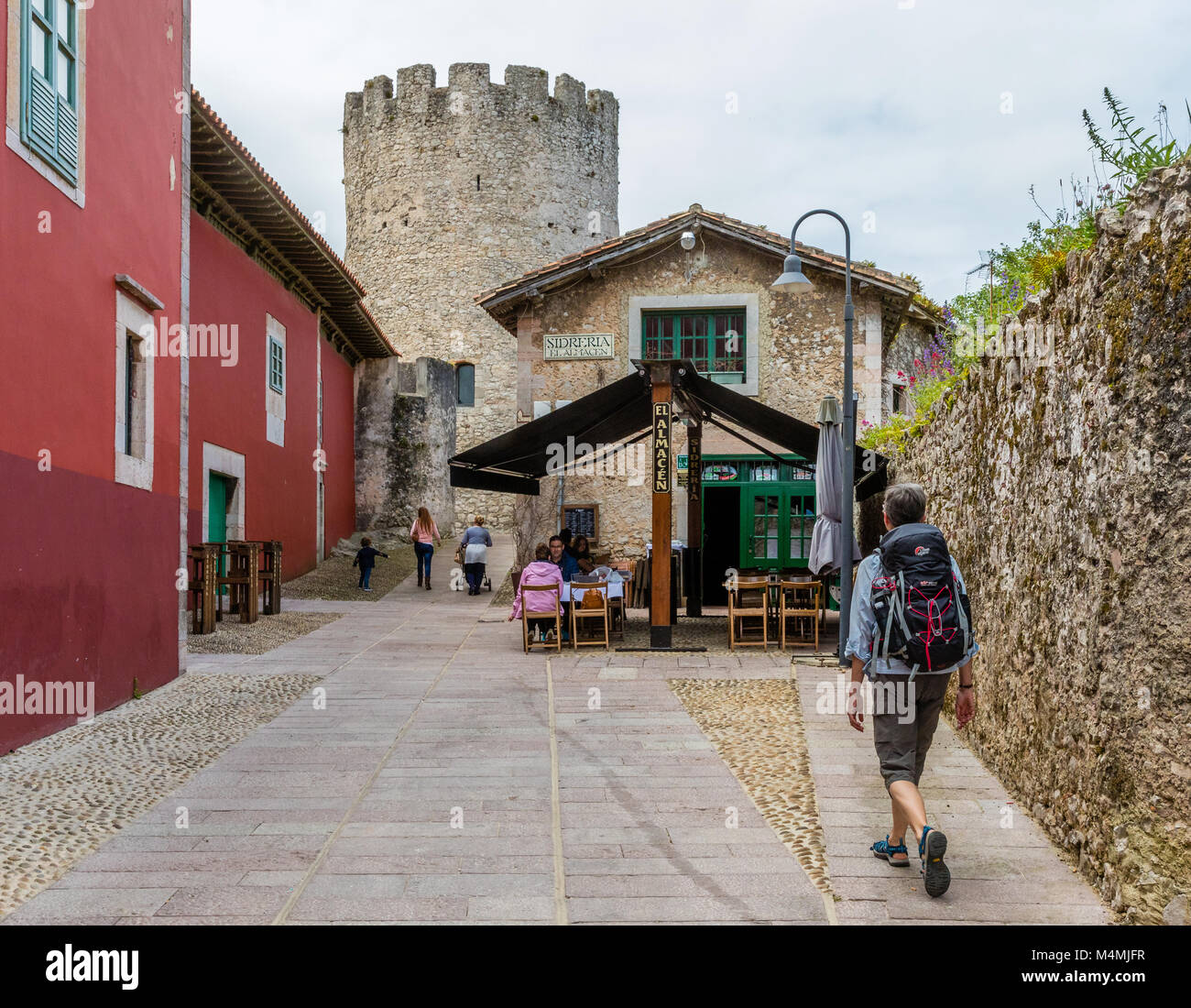 Donna con zaino in cammino verso una Sidreria o Cider house e il castello nella città di Llanes nelle Asturie spagna settentrionale Foto Stock