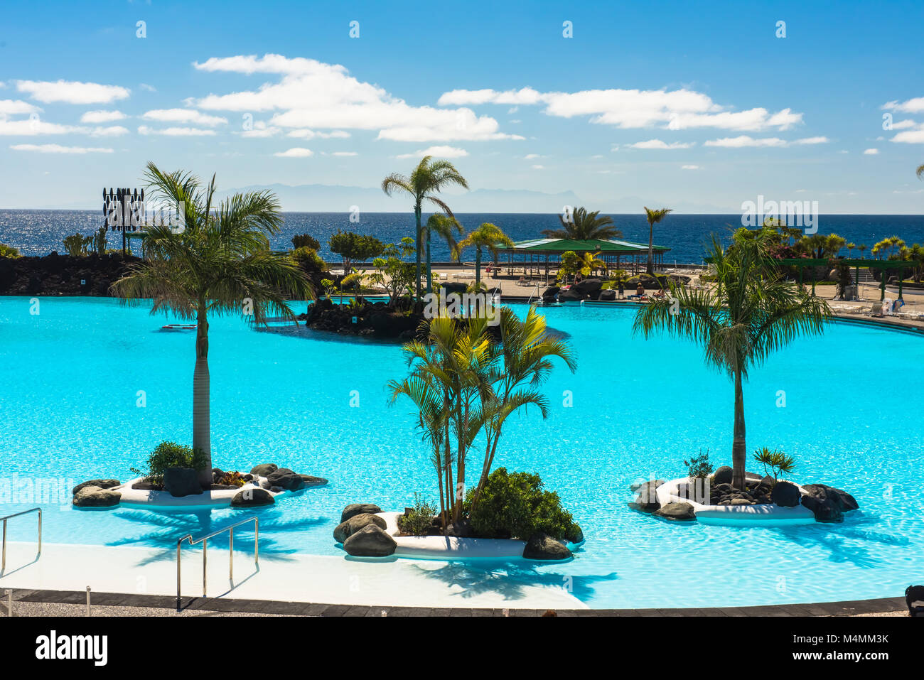 Tropical Resort piscina con sedie a sdraio, palme e vista oceano Foto Stock