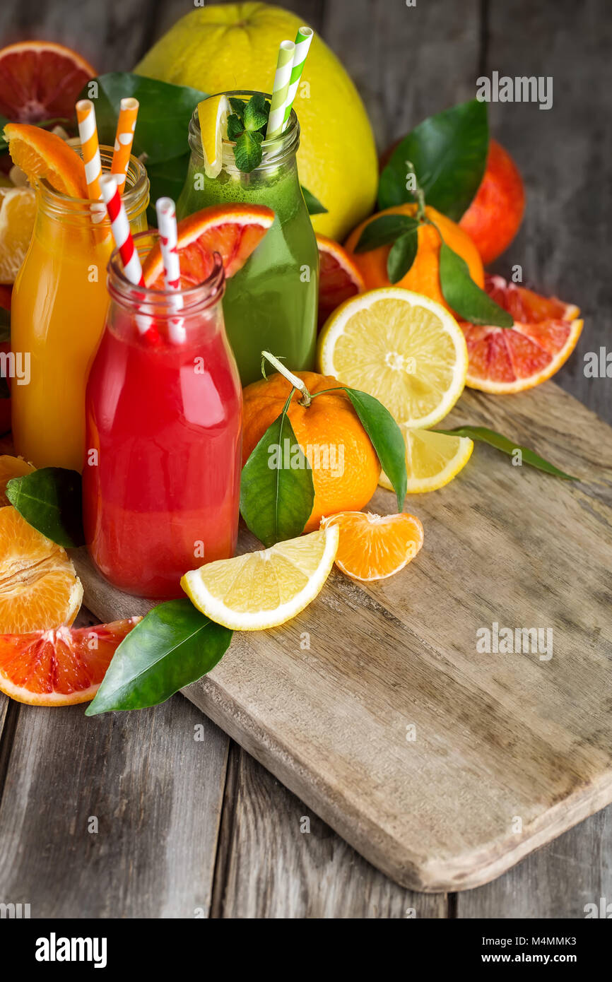 Succo di arancia, succo di arance sanguigne e limonata fatta in casa in piccoli flaconi sul vecchio tavolo in legno. Copia di sfondo spazio. Foto Stock