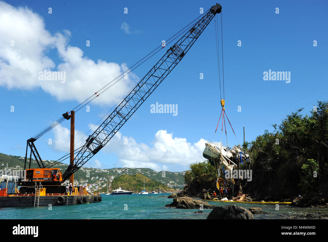 Coast Guard i membri di sorvegliare le operazioni di risolvere Marine Group, una risposta contratta company, come essi sollevare una nave spostato dai recenti uragani dal litorale di acqua Island, St. Thomas USVI, Feb 10, 2018. La costa di protezione viene qui, a sostegno degli Stati Uniti Isole Vergini dipartimento di pianificazione e delle risorse naturali, per ridurre l'inquinamento e rimuovere le navi spostato dagli uragani di Irma e Maria come parte del supporto di emergenza funzione 10 operazioni. Foto Stock