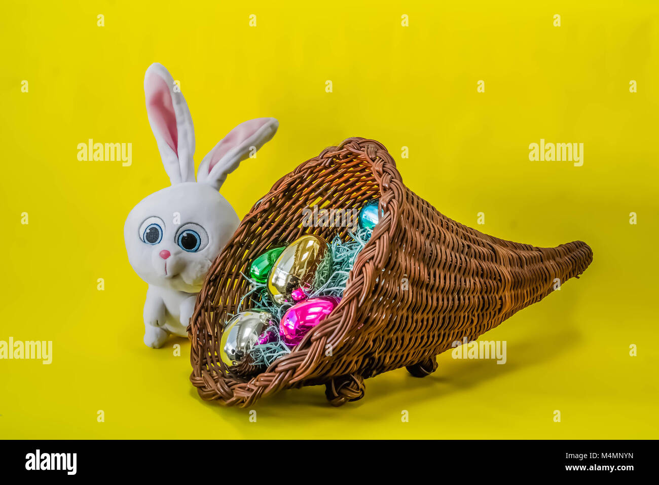 Coniglietto di pasqua con uova e cesto su uno sfondo giallo. Foto Stock