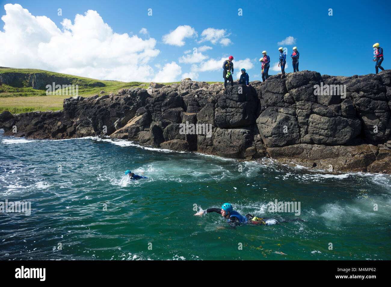 Gruppo Coasteering al Sloc, Dunseverick, Causeway Coast, paese di Antrim, Irlanda del Nord. Foto Stock