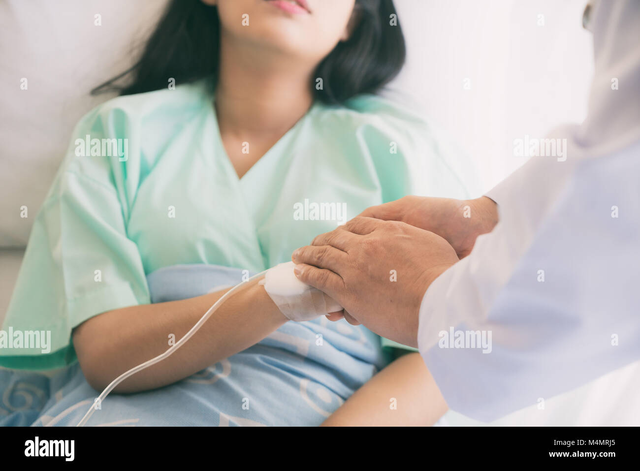 Gentile uomo medico mani tenendo la mano del paziente seduto alla scrivania di incoraggiamento, empatia, tifo e supporto durante la visita medica. Bad nuovo Foto Stock