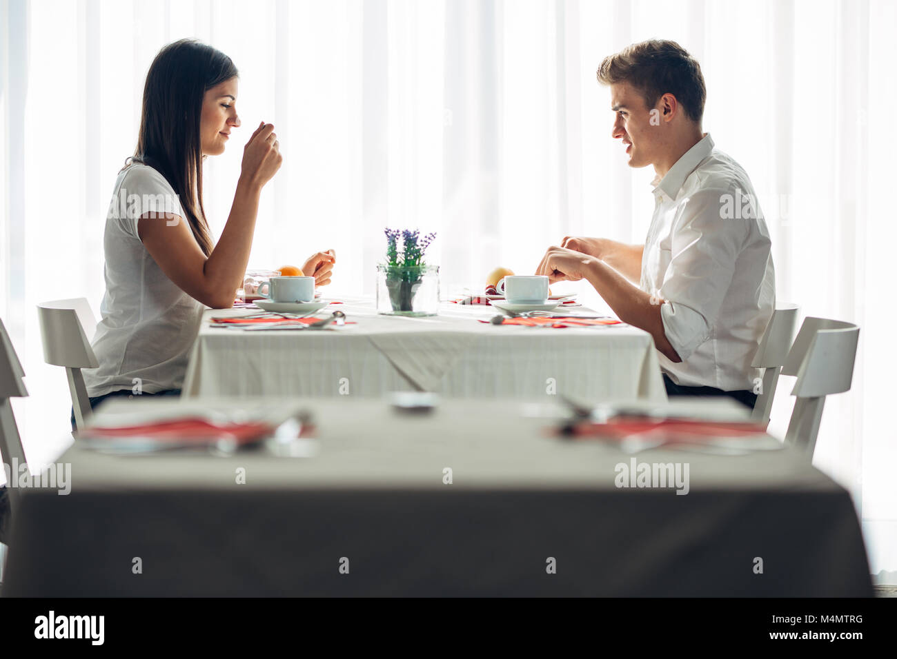 Due informale giovani adulti aventi una conversazione con un pasto.proposta formale,parlando in un ristorante.cercando cibo,offre,speciali menu.coppia felice di mangiare Foto Stock