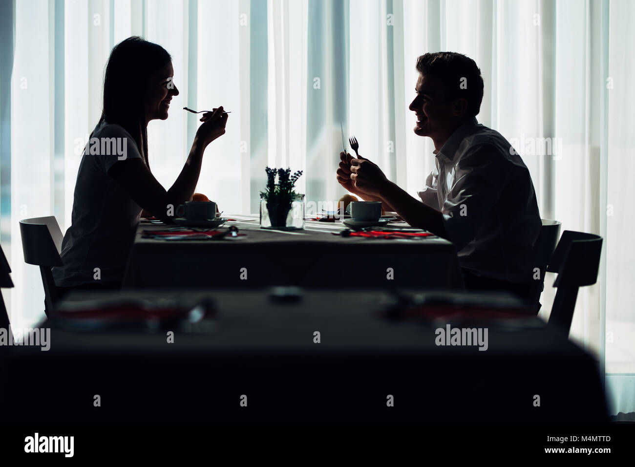 Due informale giovani adulti aventi una conversazione con un pasto.proposta formale,parlando in un ristorante.cercando cibo,offre,speciali menu.coppia felice di mangiare Foto Stock