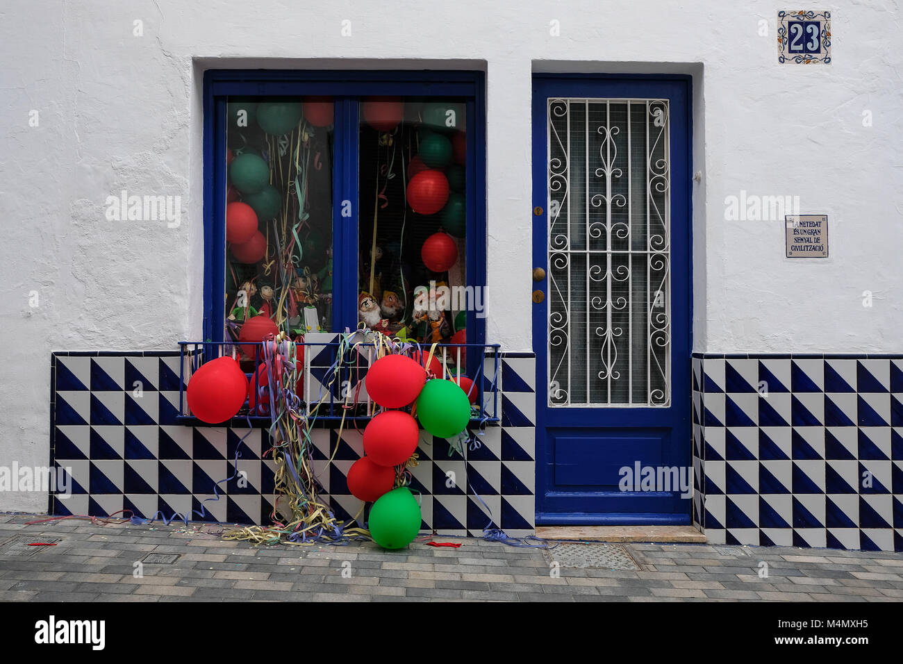 Finestra decorata con rosso e verde palloncini di gas e serpentino, giorni di carnevale in Spagna. Foto Stock