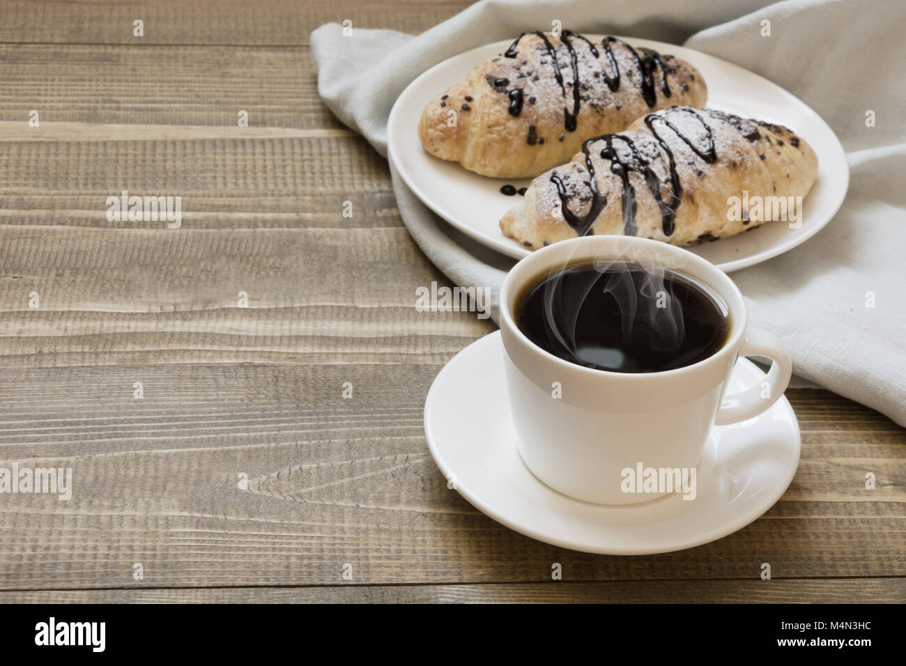 Due appena sfornato croissant al cioccolato e caffè sulla tavola di legno. Concetto di colazione. Copia dello spazio. Foto Stock