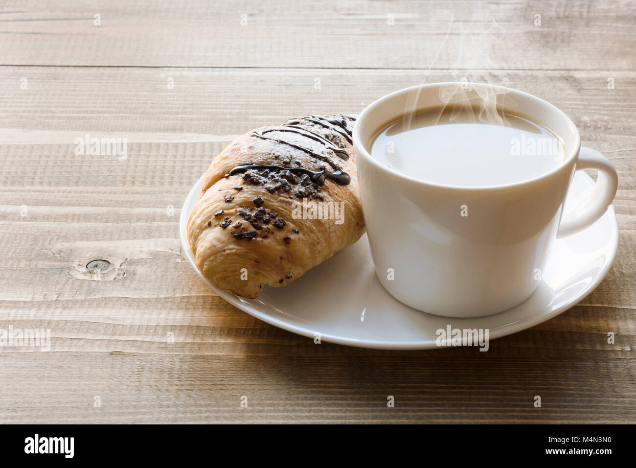 Pane appena sfornato croissant al cioccolato e caffè sulla tavola di legno. Concetto di colazione. Copia dello spazio. Foto Stock