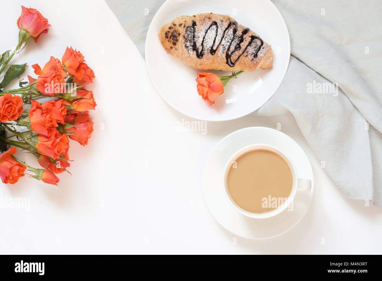 Pane appena sfornato croissant al cioccolato e la tazza di caffè sul tavolo bianco. Vista dall'alto. Colazione femmina concetto. Copia dello spazio. Foto Stock