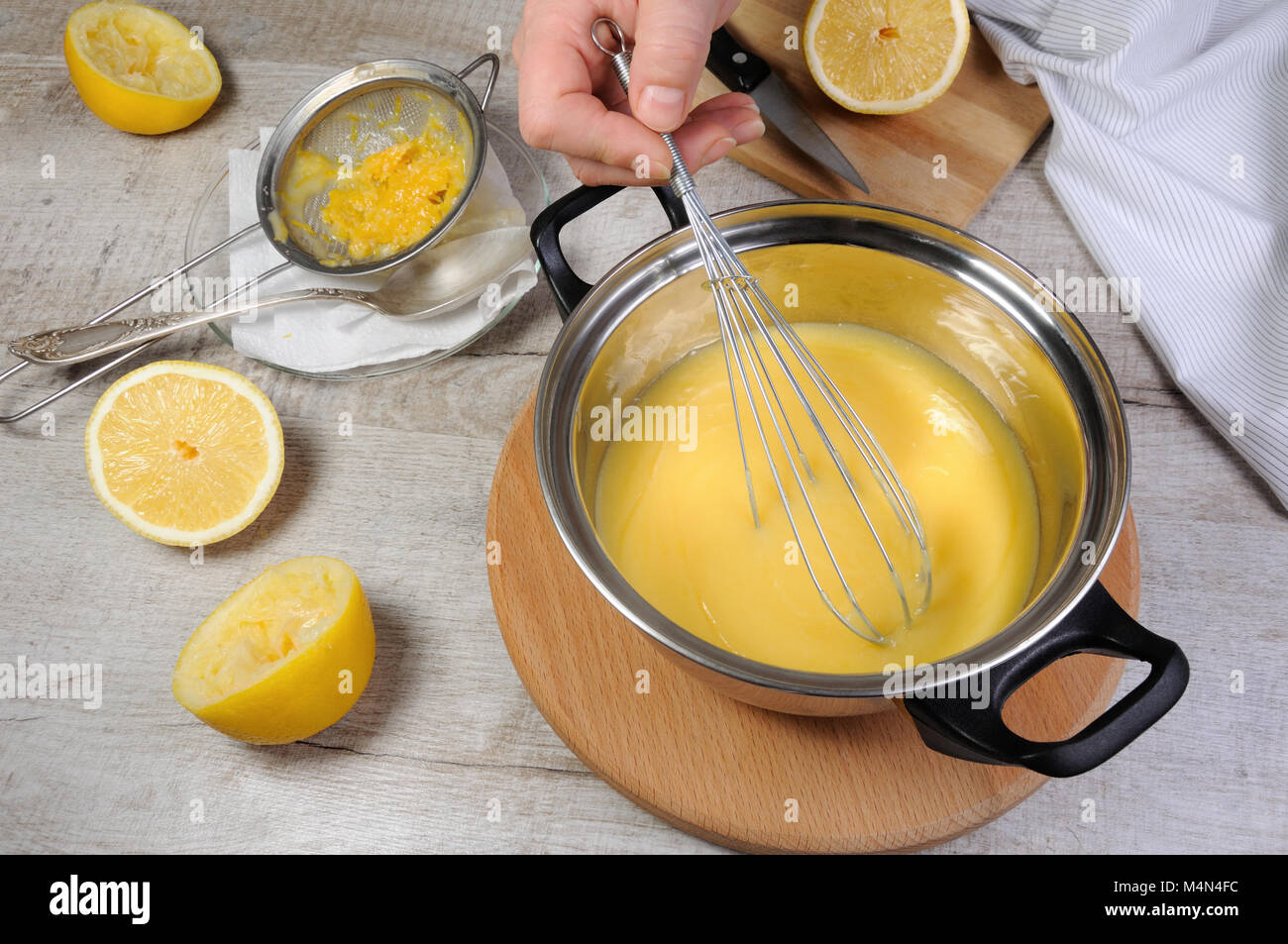 Preparato di fresco curda di limone - crema per il succo di frutta in una casseruola mantecato con frusta Foto Stock