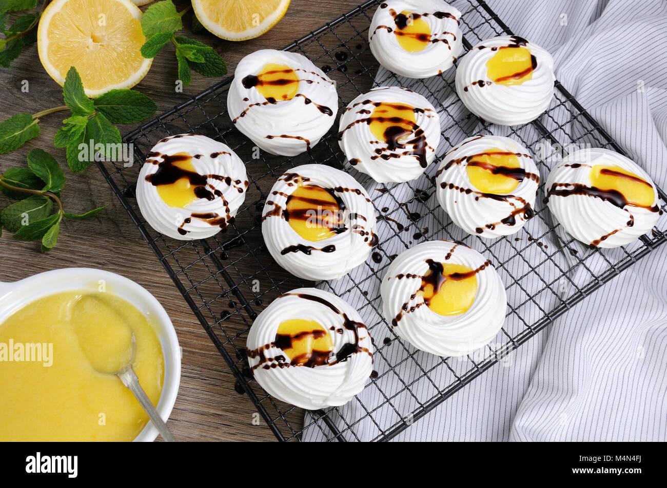 Delicato, croccante mini dessert " Pavlova' riempita con curda di limone e cioccolato topping sul rack Foto Stock