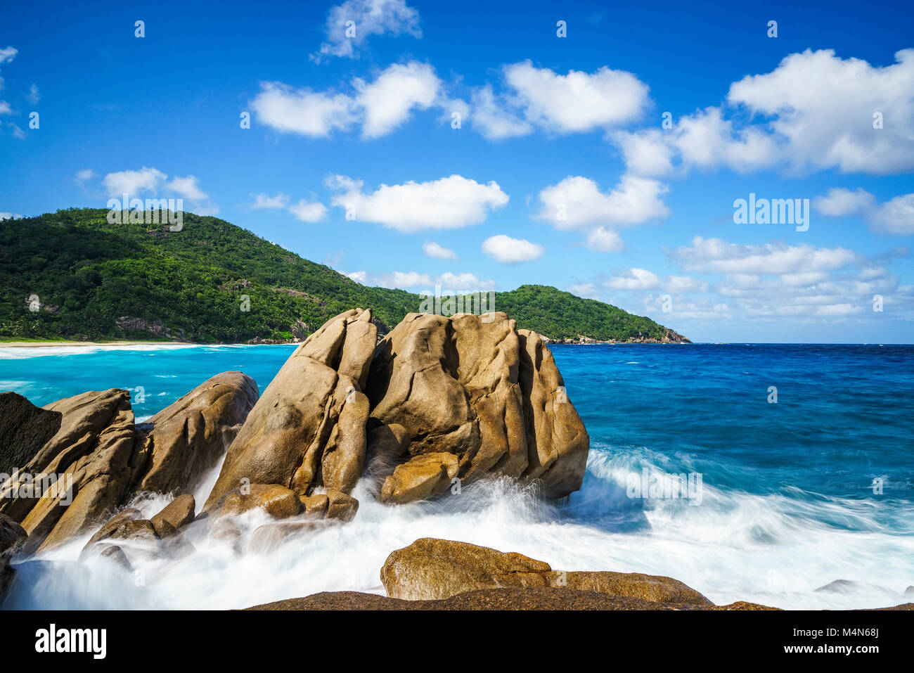 Gli spruzzi di acqua withe grandi fontane d'acqua su una selvaggia spiaggia tropicale con rocce granitiche, palme, acqua turchese sabbia bianca e blu del cielo. La polizia ba Foto Stock