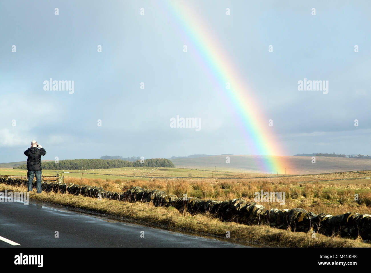 Northumberland. Xvii Feb, 2018. Regno Unito Meteo: Uomo di fotografare un arcobaleno dai militari Road (B6318) in Northumberland, Inghilterra. La strada fu costruita sotto gli ordini del generale Wade e corre parallelo al Vallo di Adriano. Credito: Stuart Forster/Alamy Live News Foto Stock