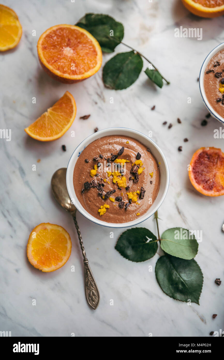 Cioccolato budino di arancione in scodelle di servizio su marmo bianco tabella Foto Stock