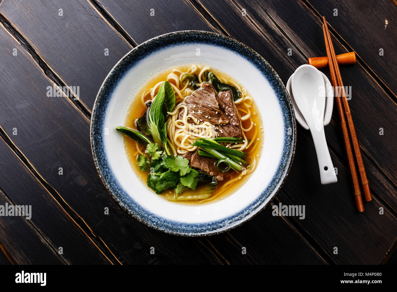 Ramen asian noodle in brodo con carne di manzo e di pak choi cavolo in ciotola di legno scuro dello sfondo Foto Stock