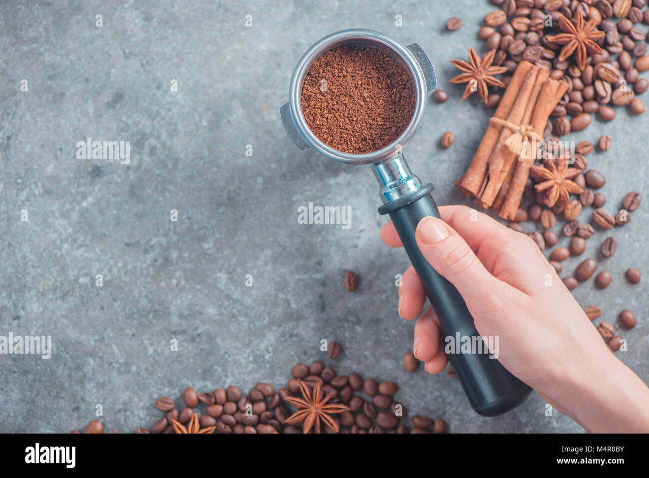 Barista mano che tiene un portafilter con caffè macinato. Immagine di intestazione con i chicchi di caffè. Vista dall'alto. Foto Stock