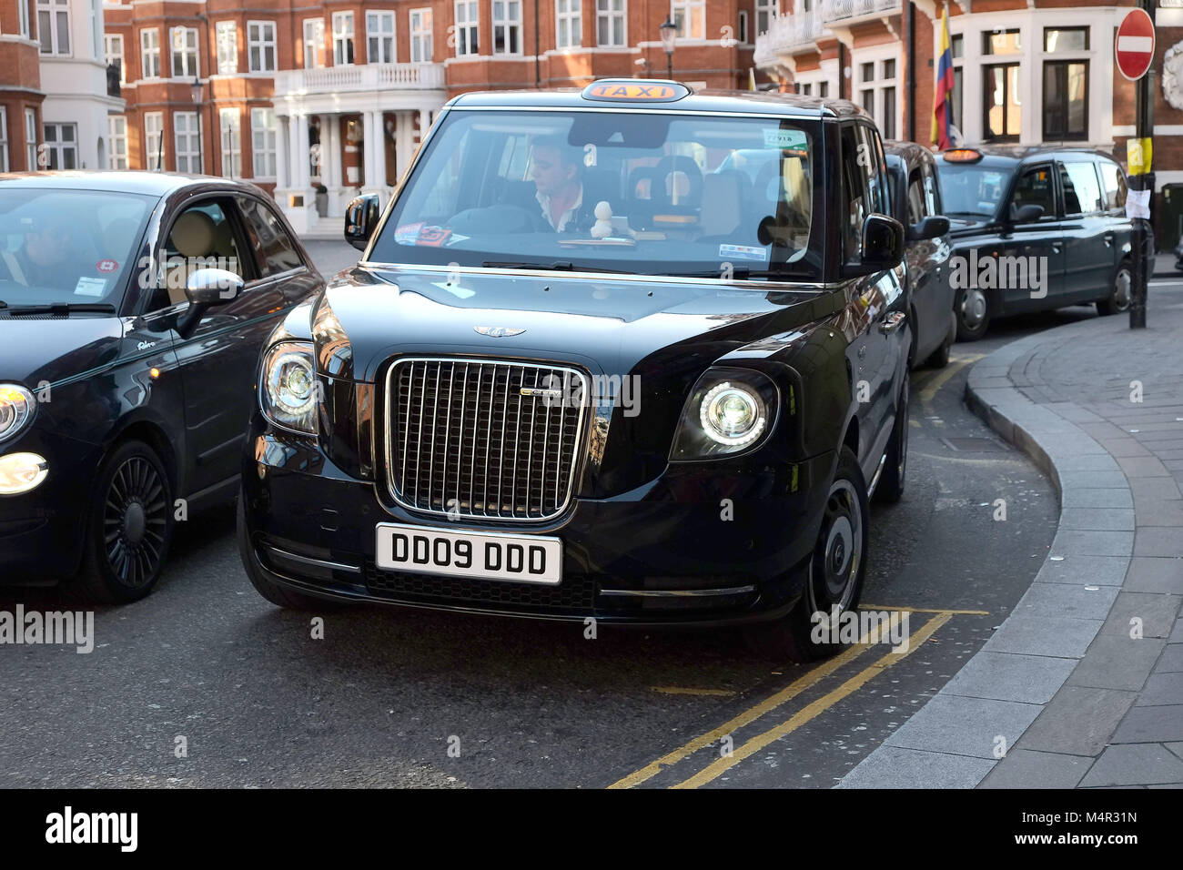 London Black Cab è andato verde come un nuovo taxi elettrico attende al di fuori di Harrods in Knightsbridge a prendere i passeggeri sul capitale nelle strade. Foto Stock