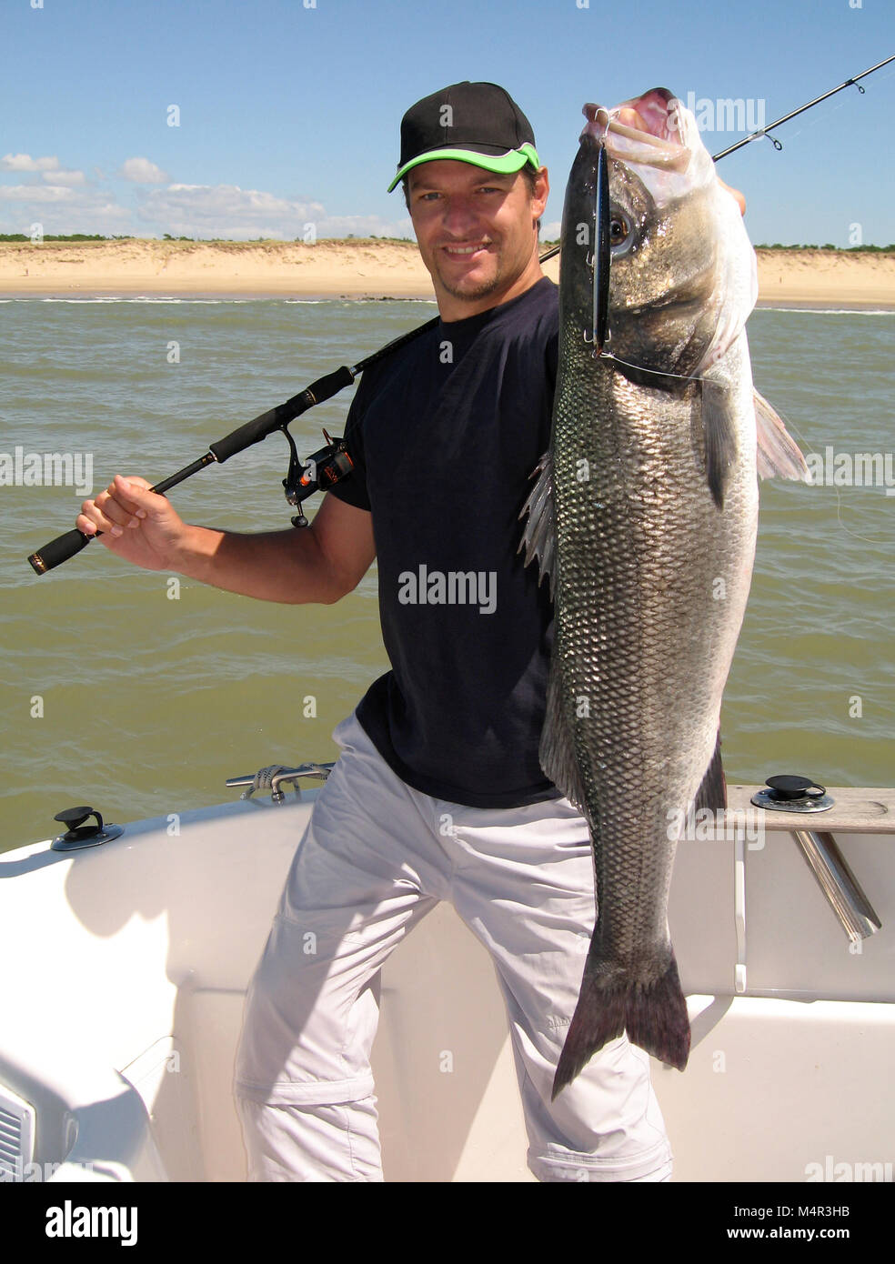 Lucky fisherman tenendo un grande mare bass Foto Stock