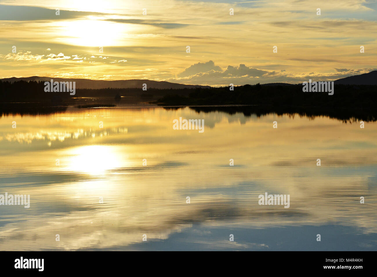 Foto del tramonto del sole di mezzanotte in Lapponia, Finlandia con acqua e fells/montagne sullo sfondo Foto Stock