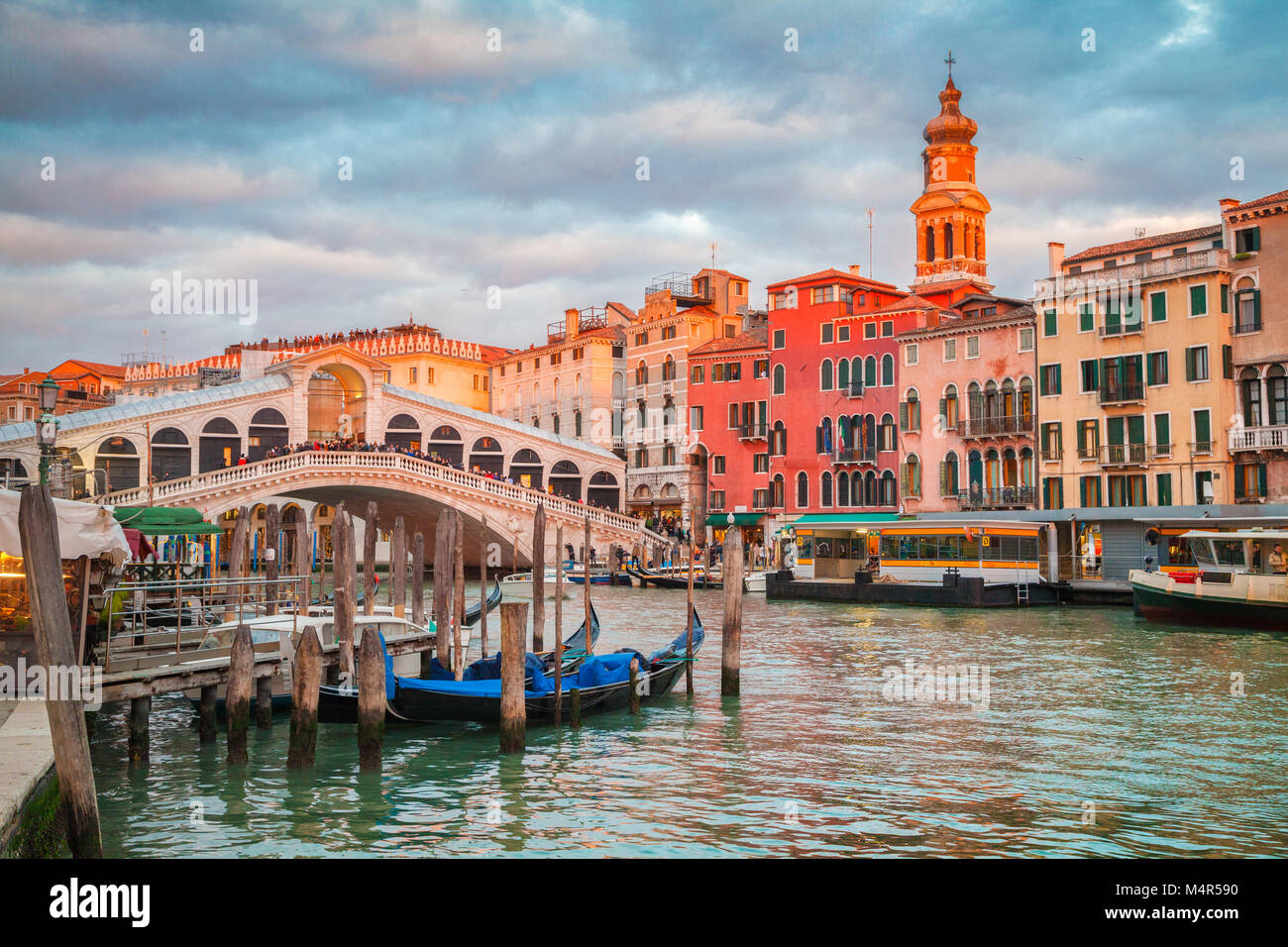 Classic vista panoramica con i tradizionali gondole sul famoso Canal Grande con il famoso Ponte di Rialto in background in beautiful Golden luce della sera Foto Stock