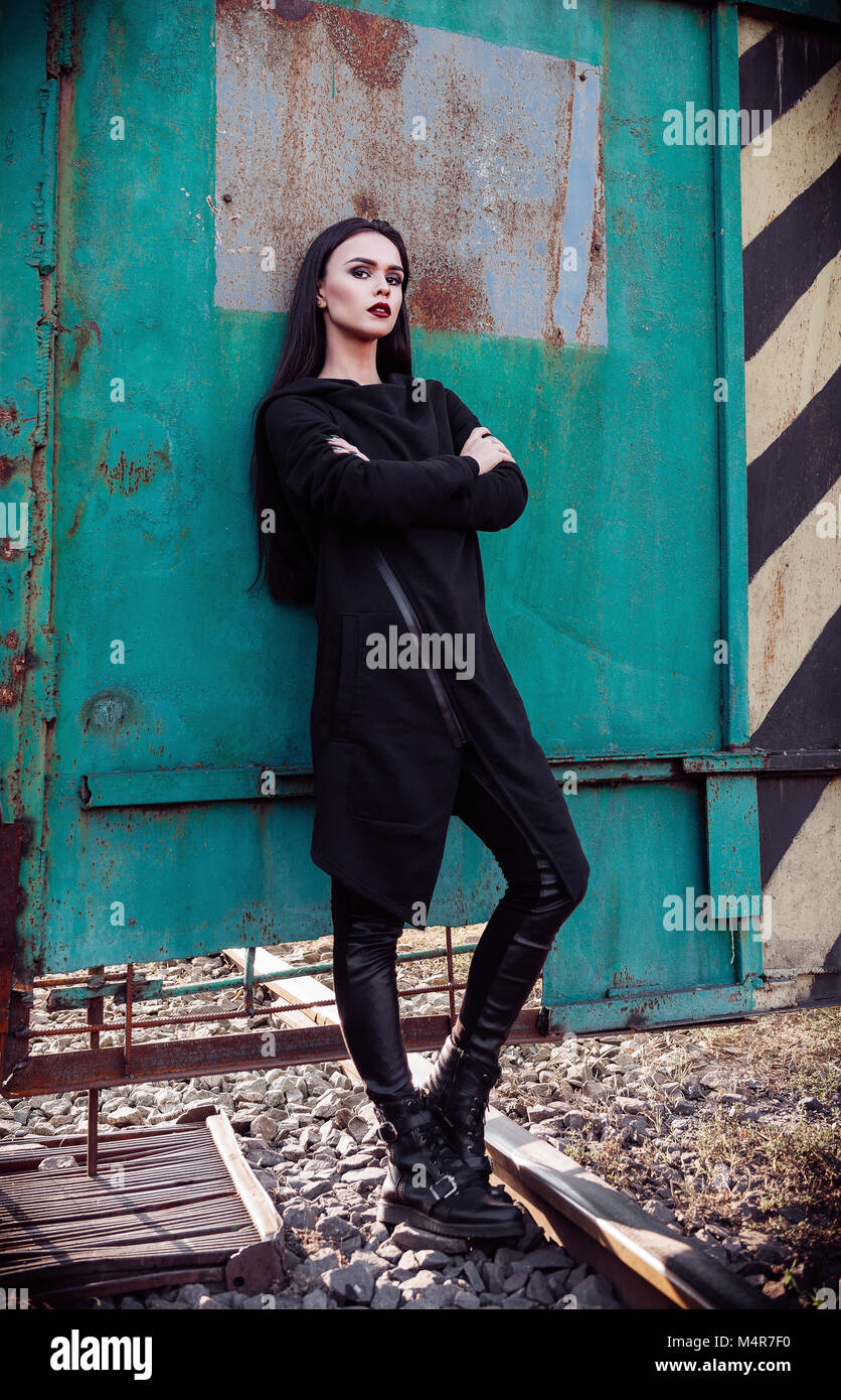 Moda shot: ritratto della cute rock girl (modello informale) in tunica e  pantaloni di pelle in piedi nella zona industriale Foto stock - Alamy