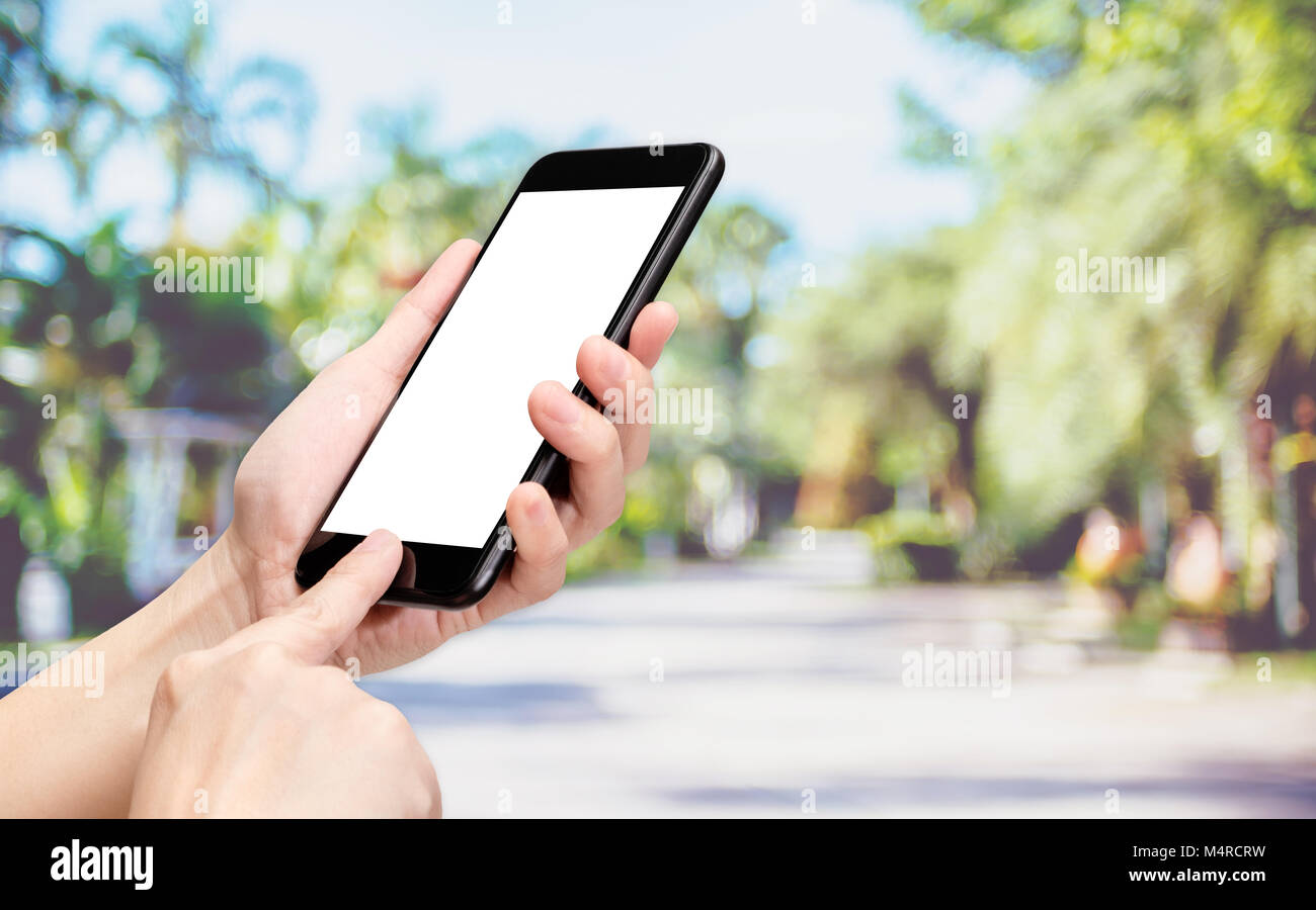 Mano fare clic su telefono cellulare con blur le persone esercitano presso il park sfondo bokeh,luce schermata bianca mock up modello per aggiungere il tuo disegno o il tuo testo Foto Stock