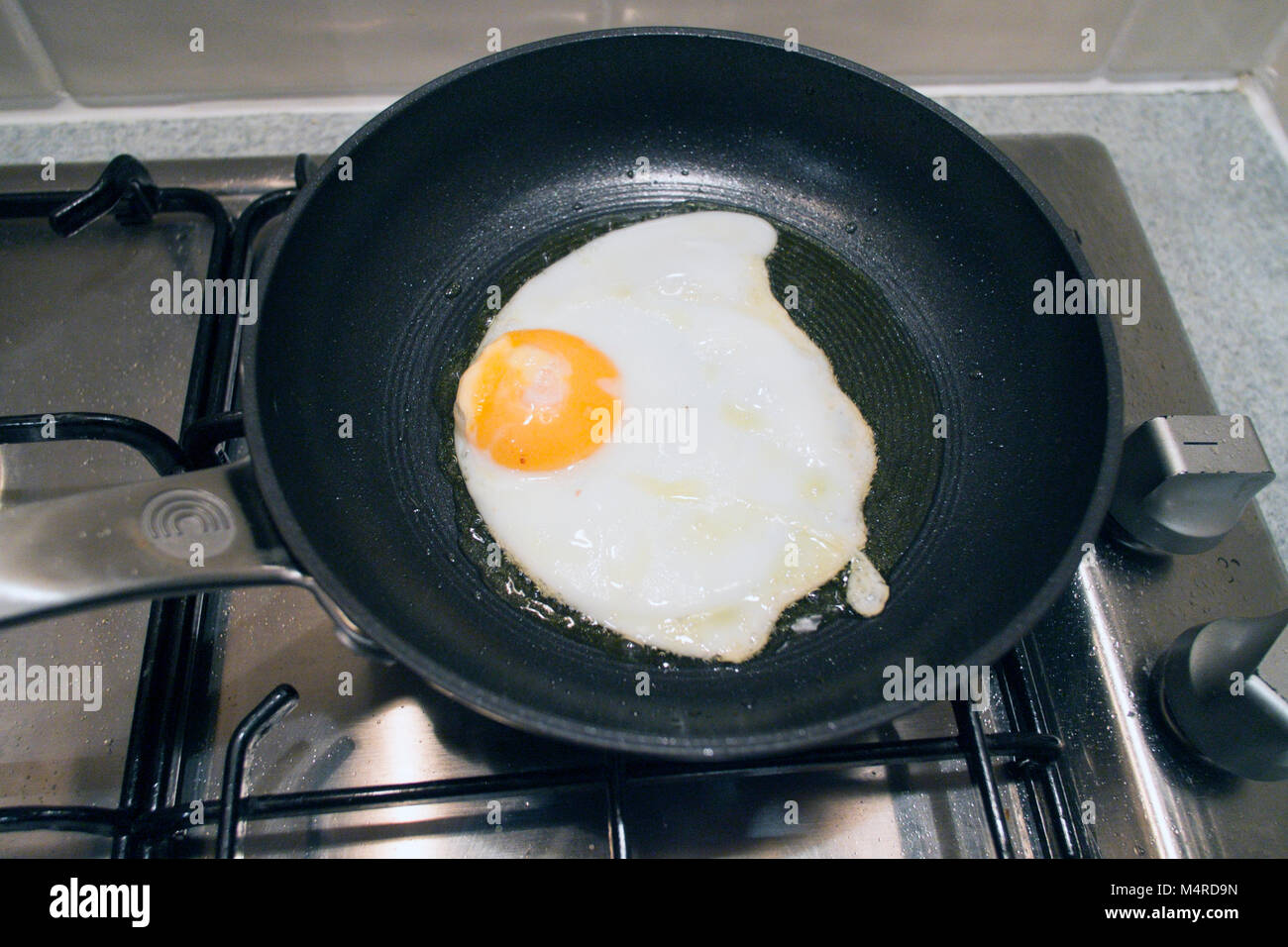 Un uovo di essere fritti in olio di oliva in una piccola rivestita in  teflon antiaderente padella su un piano cottura a gas Foto stock - Alamy