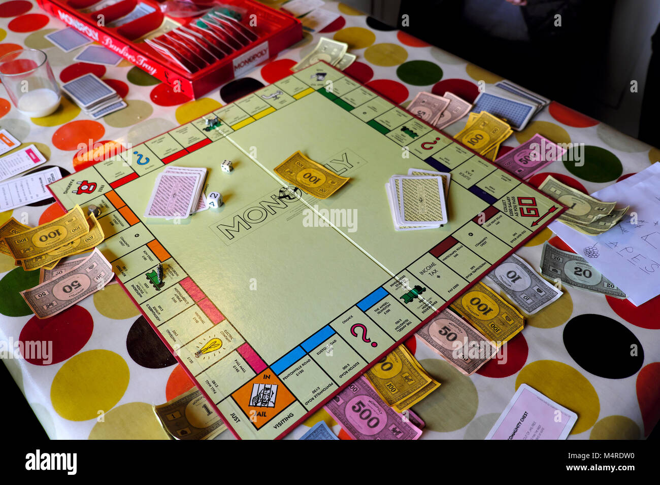 Scheda di monopolio gioco che viene giocato da bambini all'interno di una casa su un tavolo con la tovaglia colorato a metà termine in Carmarthenshire Wales UK Foto Stock