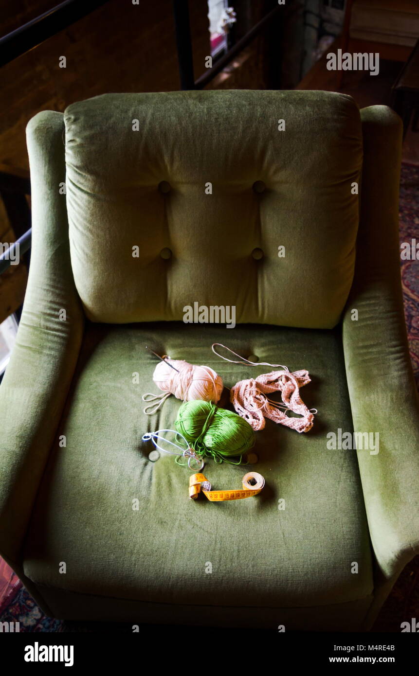 Strumenti a crochet su un comodo divano verde sedia Foto Stock