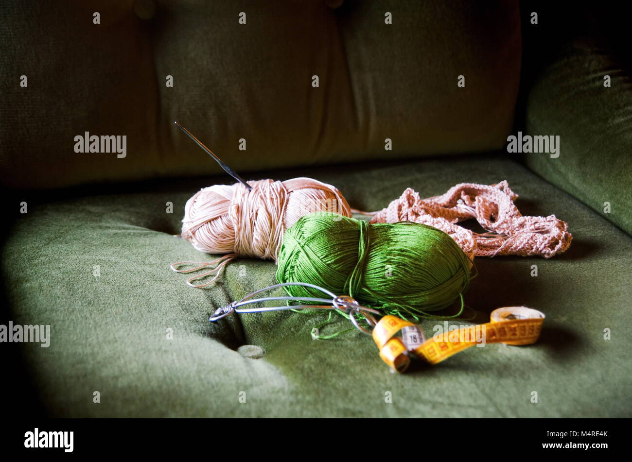 Strumenti a crochet su un comodo divano verde sedia Foto Stock
