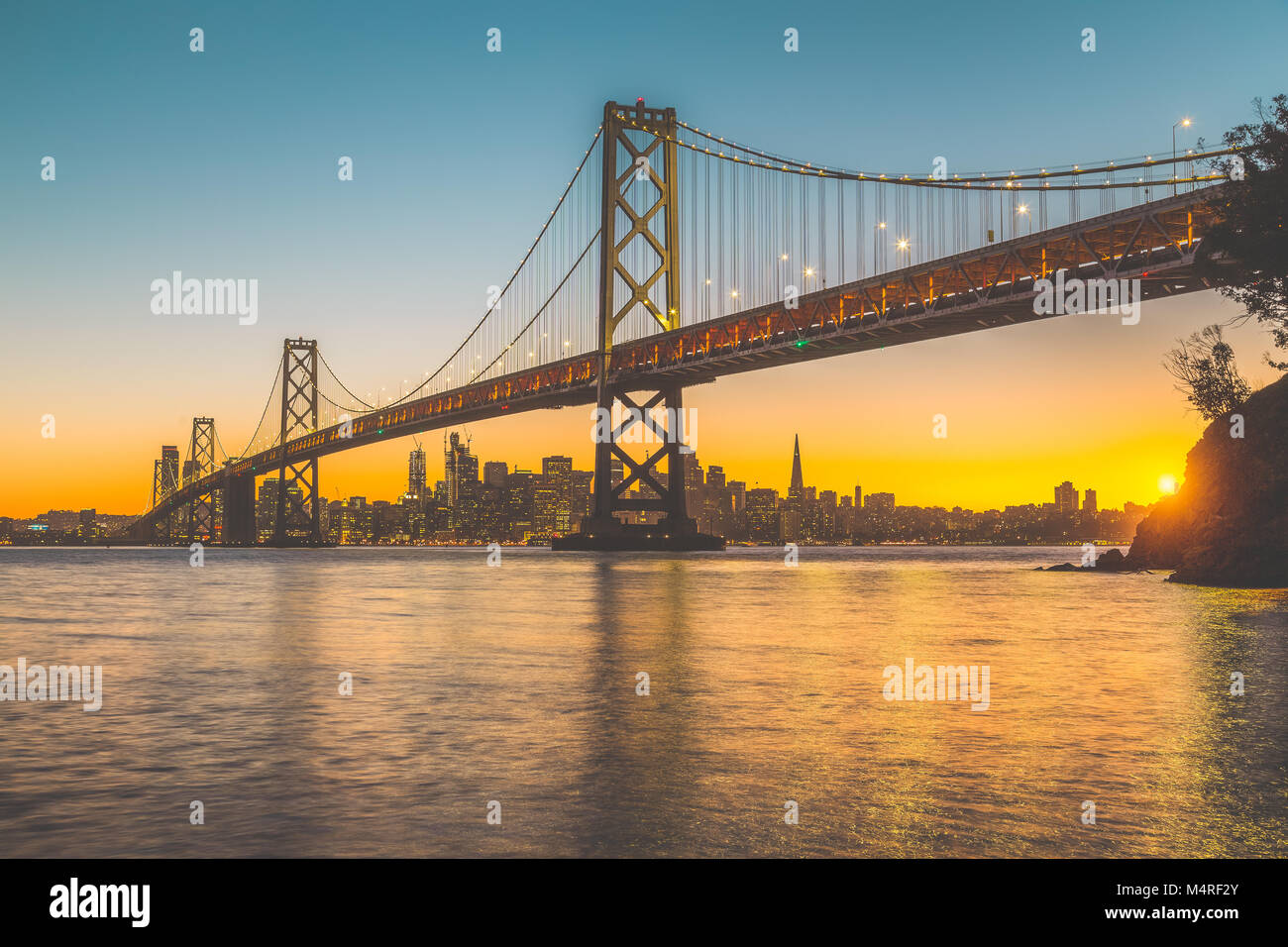 Classic vista panoramica dello skyline di San Francisco con il famoso Oakland Bay Bridge illuminato nel bellissimo golden luce della sera al tramonto in estate, San Foto Stock