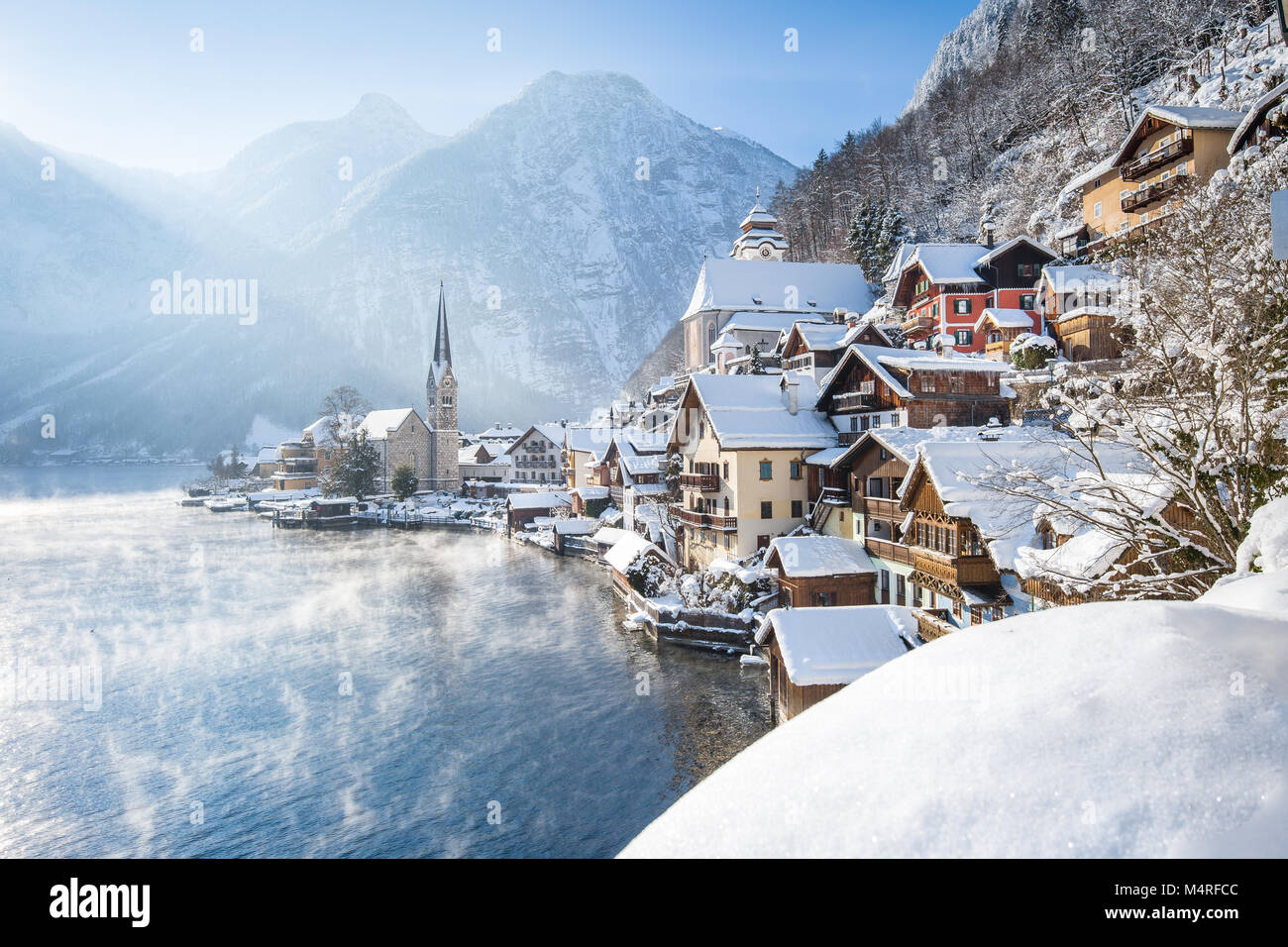 Classic vista da cartolina famosa Hallstatt Lakeside Town nelle Alpi su una bella fredda giornata soleggiata con cielo blu e nuvole al sorgere del sole in inverno, Salzk Foto Stock